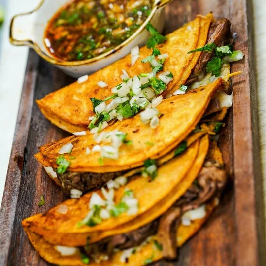Birria tacos overhead view with consomme and lime at Ixtapa Mexican Restaurant, Lunenburg MA